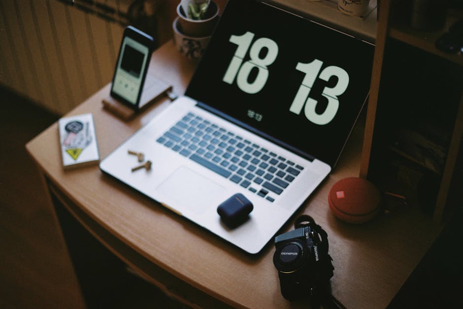A cozy home workspace with a laptop, smartphone, camera, and headphones.