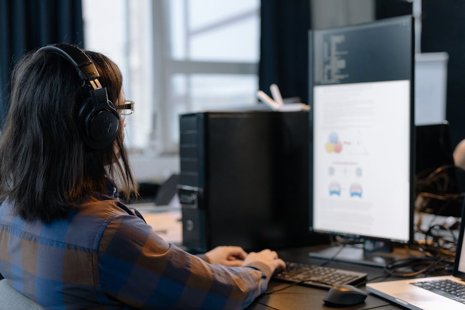IT professional working on a computer in a modern office setting.