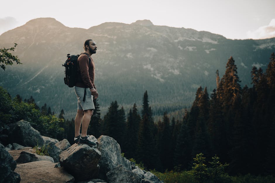 A man stands on rocky terrain, admiring the breathtaking mountain view at sunset, embodying adventure and exploration