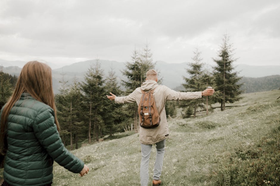 Couple exploring a scenic mountain landscape with lush greenery on an overcast day